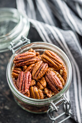 Peeled pecan nuts in jar on kitchen table.