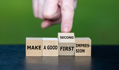 Symbol for a second chance. Hand turns wooden cube and changes the expression 'make a good first impression' to 'make a good second impression'.