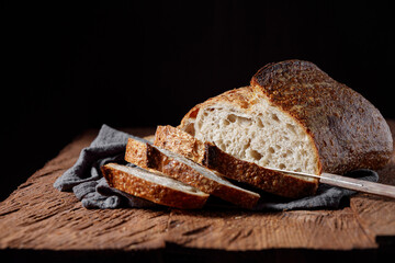 Rustic sourdough bread with cut slices on a wooden table. 