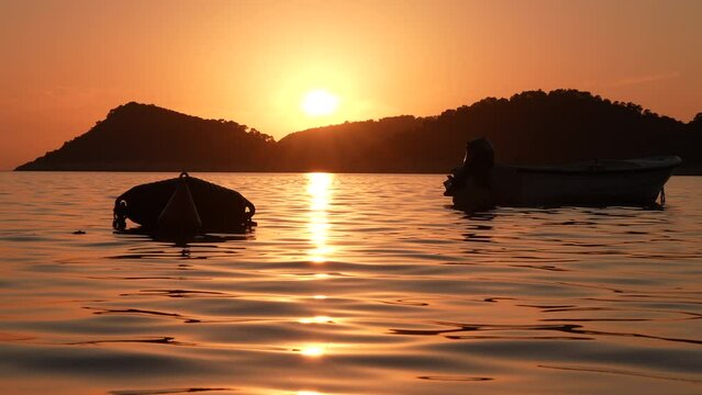 Silhouette of boats on the sea, sun setting in the background