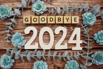 Goodbye 2024 alphabet letters with flower decorate on wooden background