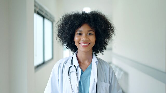 Friendly African American Female Medical Doctor Looks at Camera and Smiles. Successful Black Health Care Physician in White Lab Coat