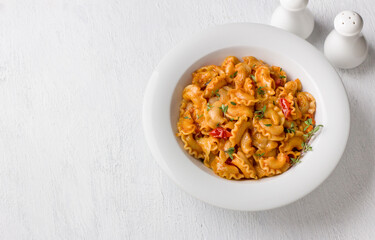 Simple pasta with tomato sauce sprinkled with fresh thyme in a white plate on a light gray background, top view, flat lay. Delicious homemade food