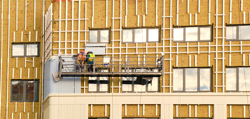 Builders repair walls of facade of house using mineral insulation and panels during construction...