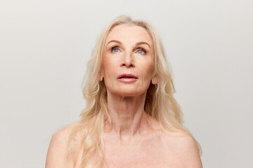 Portrait of beautiful middle-aged, mature woman with well-kept natural skin posing over grey studio...