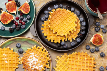 Belgian waffles in a pan and on a plate. Berries and figs, a cup of tea.