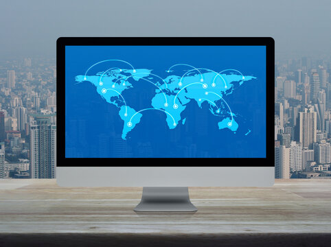 Connection line with global world map on computer monitor screen on wooden table over city tower and skyscraper, Technology communication online concept, Elements of this image furnished by NASA