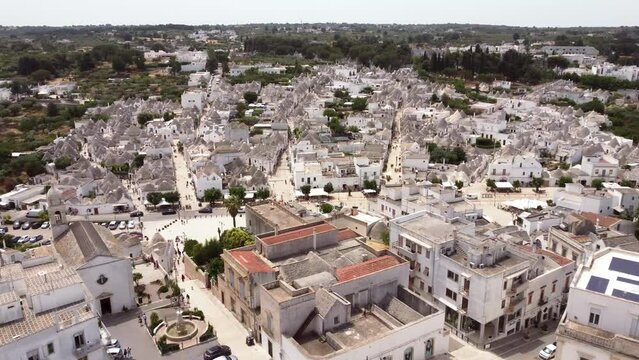 Aerial drone footage of Alberobello, Puglia, Italy main streets. Establish scene of  traditional whitewashed, conical roof (trulli) UNESCO world heritage site, landmark tourist destination from above