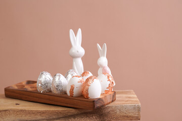 Easter decoration: eggs with silver and rose-gold metallic foil in a bamboos form on a wooden...