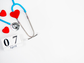 Stetascope with hearts on a light-coloured background with calendar. Concept of medicine, treatment, health. World Health Day.