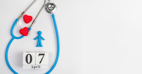Stetascope with hearts on a light-coloured background with calendar and human figures. Concept of medicine, healing, health. World Health Day.