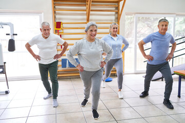 Smiling senior males and females exercising at rehab center