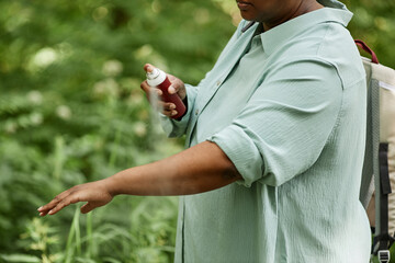 Side view closeup of black woman spraying arms with bug repellent outdoors in nature, copy space  - obrazy, fototapety, plakaty