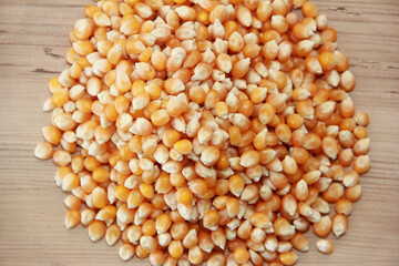 Small grains of natural dry yellow corn on a brown wooden background