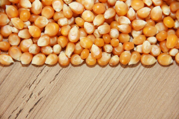 Small grains of natural dry yellow corn on a brown wooden background