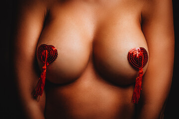 Burlesque dancer with red adhesive glittery Burlesque nipple pasties breast covers.