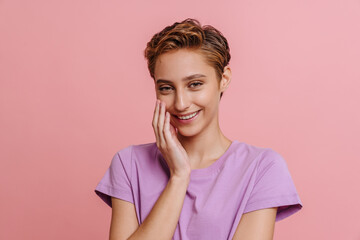 Young short-haired beautiful smiling woman in t-shirt touching her cheek
