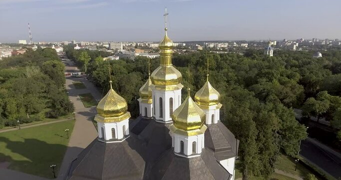 Drone flight, all-round panorama, golden domes with crosses of the Church of St. Catherine's Cathedral against the backdrop of the park and Chernigov in the morning sun