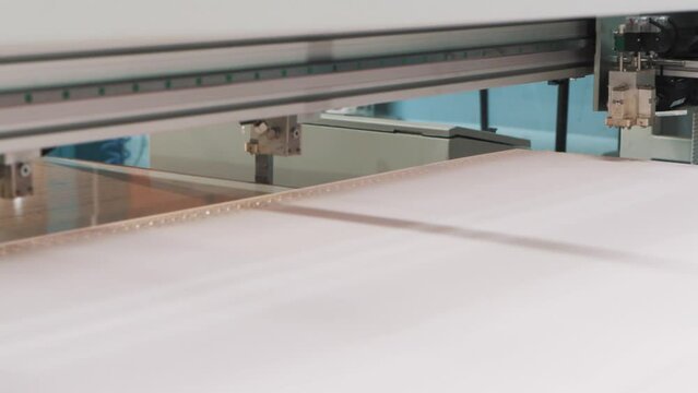 A close-up of a computer-aided machine applying automatic glue to foam for the manufacture of a mattress in a textile factory.