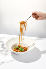 Woman eat italian pasta with tomato and basil. Female hand holding fork with spaghetti over dish...
