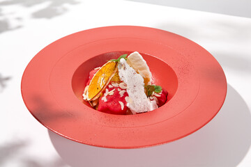 Summer dessert - berry sorbet with citrus and crispy waffles. Strawberry gelato on red ceramic plate. Frozen dessert from strawberry Homemade sorbet with citrus and fruit in restaurant plate