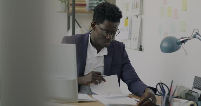 Serious office worker writing business document working alone in office room. Professional occupation and ambitious businesspeople concept.