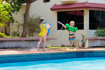 Kids play with water hose at swimming pool.