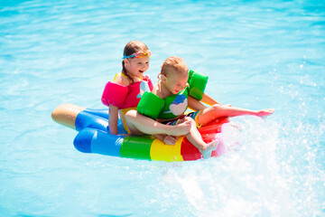 Kids on inflatable float in swimming pool.