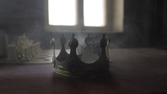 Beautiful crown miniature on chessboard. chess board game concept of business ideas. Chess figures on a dark background with smoke and fog. Selective focus