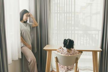 Introverted mother with her daughter in her room : Stressed mother looks at little daughter worried...
