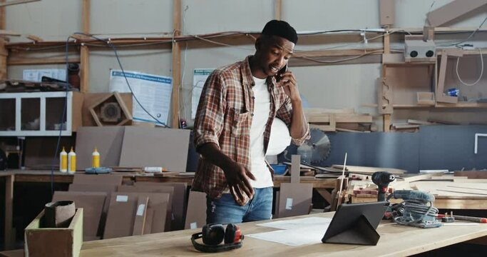Young African man on cell phone in factory