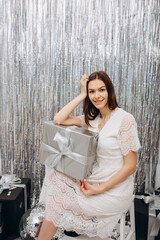 foil rain curtain for the photo zone. beautiful girl in a white dress and photo booth in silver style. mirror disco ball and silver confetti