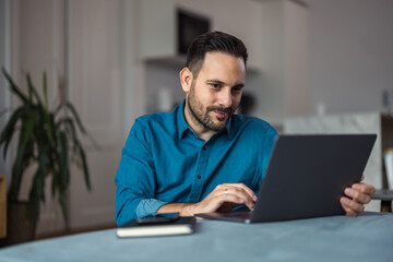 Focused businessman working over the laptop, sitting at the home office.