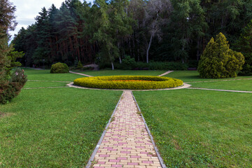 Obraz premium Mowed lawns, green trees and beautiful roads. Autumn landscape of the park.