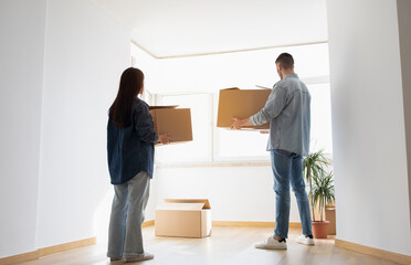 Fototapeta na wymiar Young Couple Moving Home Together, Carrying Big Cardboard Boxes In Hands