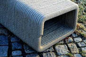 park bench has a concrete tube base flattened on the sides. the bench is printed on a 3d printer...