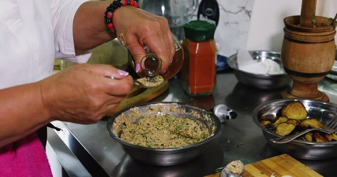 Pouring vinegar in tablespoon to add to spread in bowl on kitchen desk.