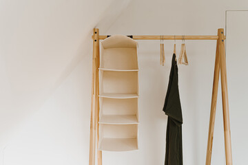 Women's fashion wardrobe. Stylish female evening dress on floor hanger over white wall. Minimalist...