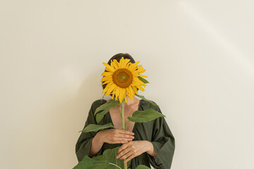 Woman in green evening dress holds sunflower in hands