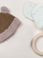 A delicate flat on a beige background with a knitted cap and booties for a baby, a newborn.