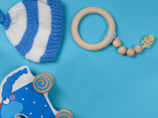 The background is baby blue. With a wooden rattle, a blue wooden elephant and a knitted cap for...