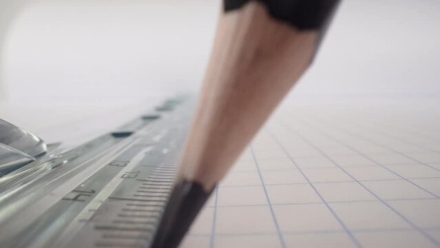 Macro drawing straight line with pencil and transparent plastic ruler on white paper exercise book, extreme close-up shot