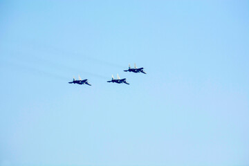 Fighter planes are flying as a Vic formation against isolated blue sky