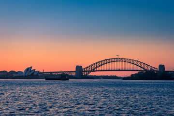 Sydney Harbor Bridge and Opera House during Sunset seen from the Sea, New South Wales, Australia.