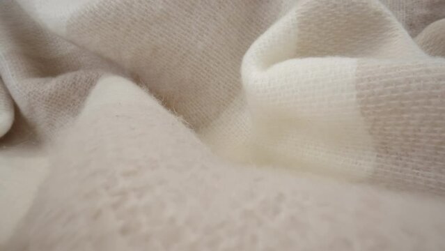 Macro shot of wool fabric plaid, scarf or sweater. Slider dolly close-up wool textile beige color texture. Laowa probe lens camera glides over detailed knit material