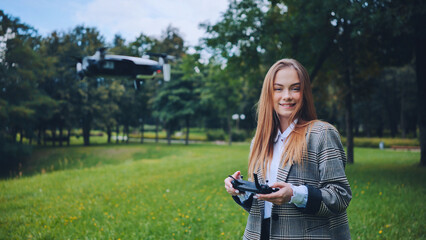 A cute girl controls a drone in the park.
