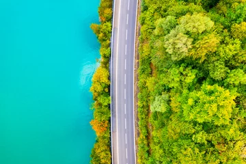 Papier Peint photo Lavable Turquoise The road near turquoise lake. Aerial landscape. The road by the lake in Switzerland. Summer landscape from the air. Forest and road with curves.