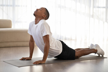 Fototapeta premium Black guy doing morning yoga practice at home