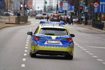 Radiowóz polskiej policji drogowej z policjantem, nowy podczas służby w mieście. Nowe barwy - obrazy, fototapety, plakaty