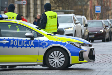Radiowóz polskiej policji drogowej z policjantem, nowy podczas służby w mieście. Nowe barwy - obrazy, fototapety, plakaty